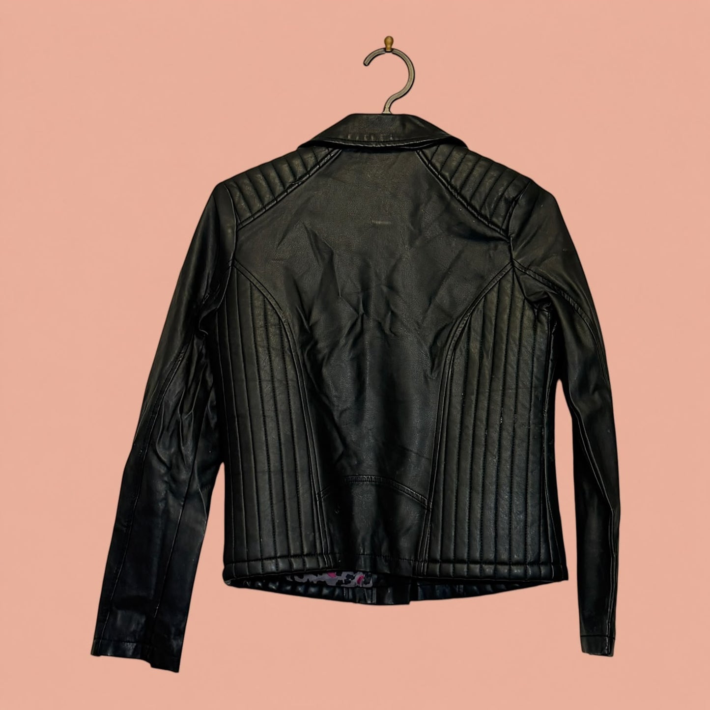 Chaqueta de eco cuero negra de segunda mano de Tuclosetrenovado.cl con detalles acolchados en la espalda