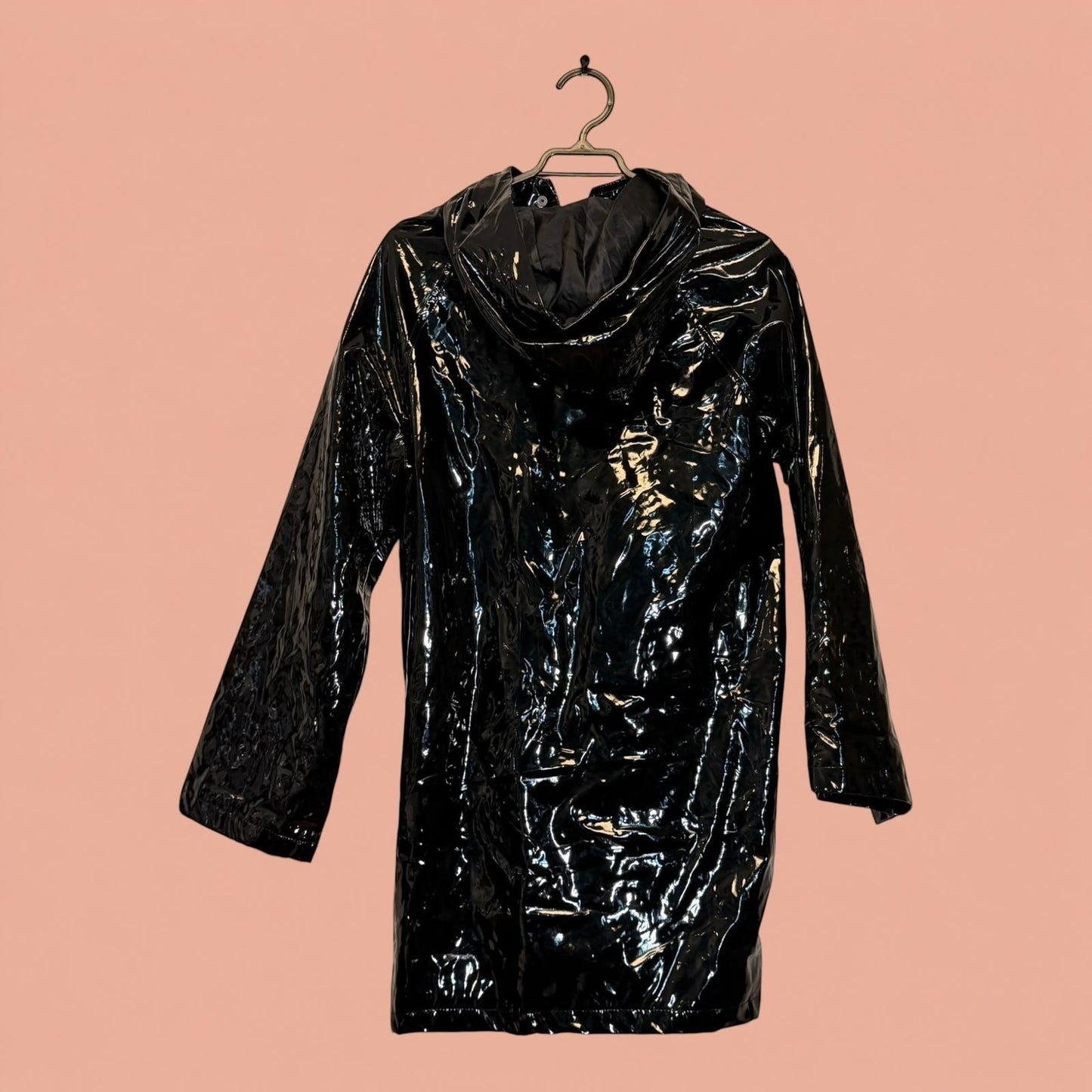 Chaqueta impermeable negra de eco cuero brillante con capucha de Tuclosetrenovado.cl, estilo moderno y elegante.