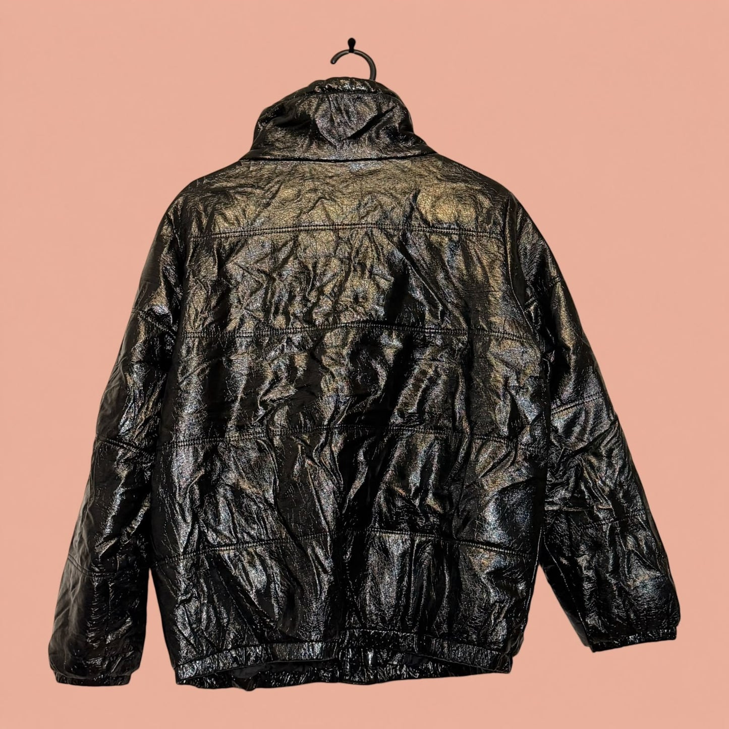 Chaqueta acolchada de eco cuero negro con acabado brillante de Tuclosetrenovado.cl, vista trasera en percha.