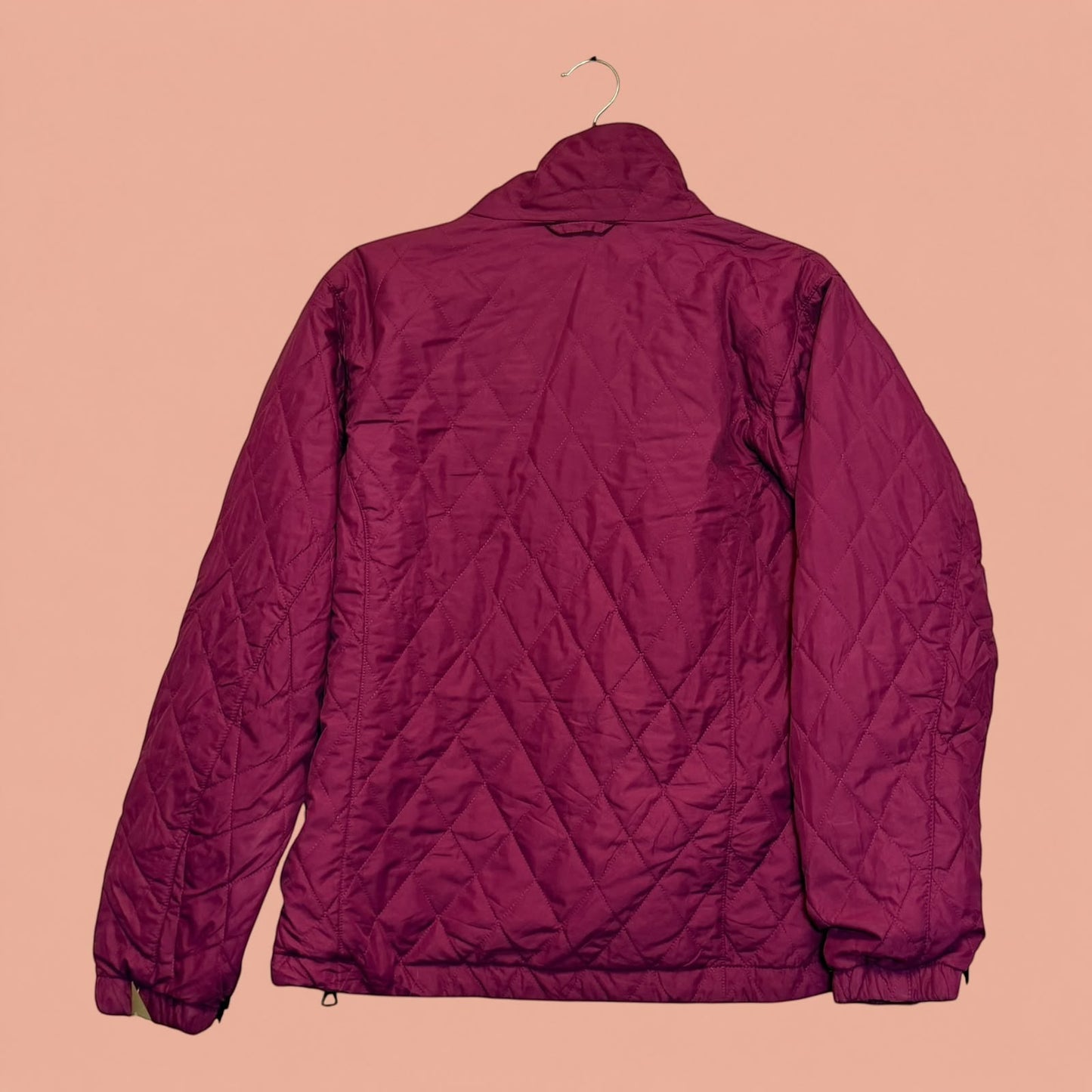 Chaqueta acolchada color burdeos de Tuclosetrenovado.cl con diseño de rombos, vista trasera sobre fondo rosa