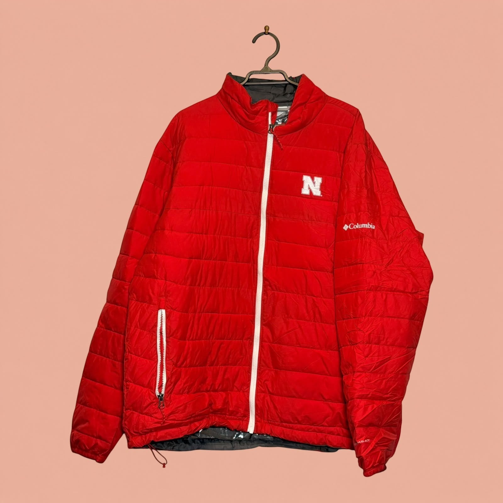 Chaqueta acolchada roja Columbia de Tuclosetrenovado.cl con cremallera blanca y logo de la letra N en el pecho
