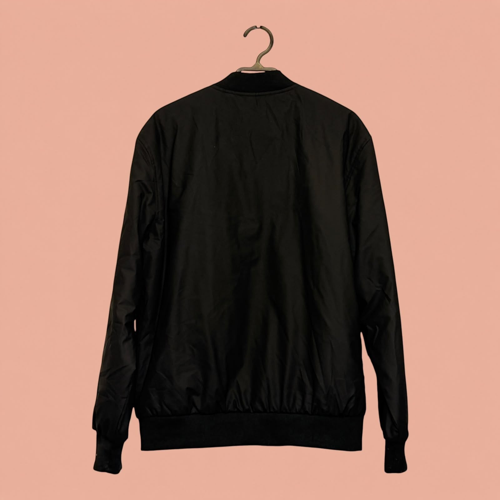 Chaqueta bomber negra de eco cuero para hombre de Tuclosetrenovado.cl vista trasera sobre fondo rosado