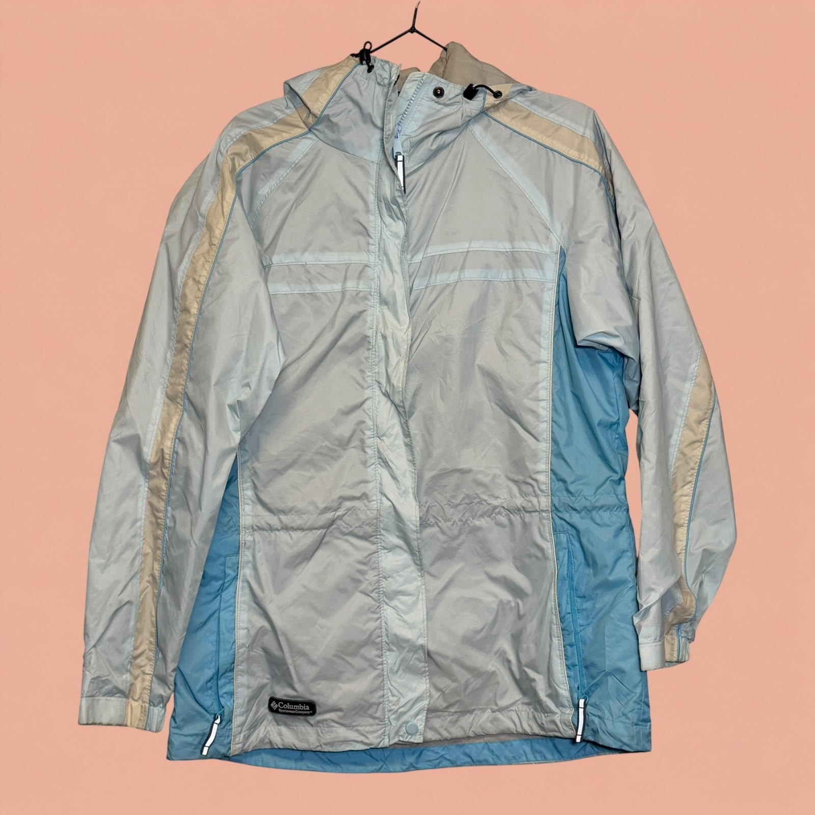 Chaqueta cortavientos Columbia de Tuclosetrenovado.cl en tonos azul claro y beige con capucha y cierre frontal