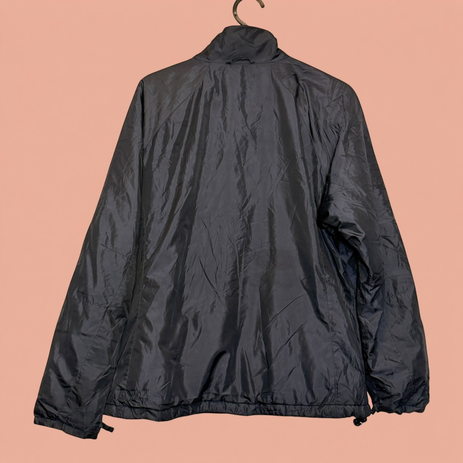 Chaqueta cortavientos negra de segunda mano de Tuclosetrenovado.cl, vista trasera con ajuste en la cintura