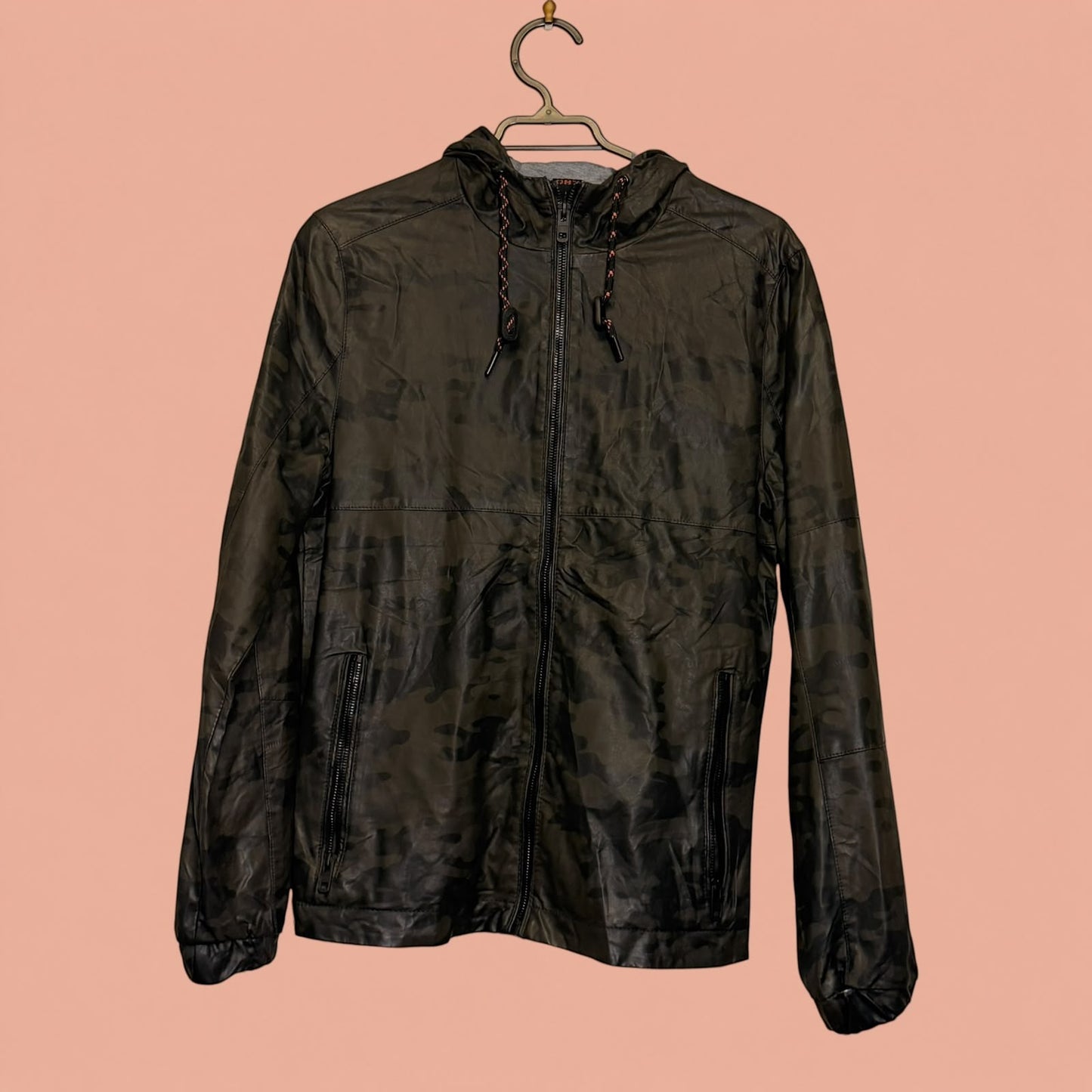 Chaqueta de hombre Tuclosetrenovado.cl de eco cuero negro con estampado camuflaje, cierre frontal y capucha.