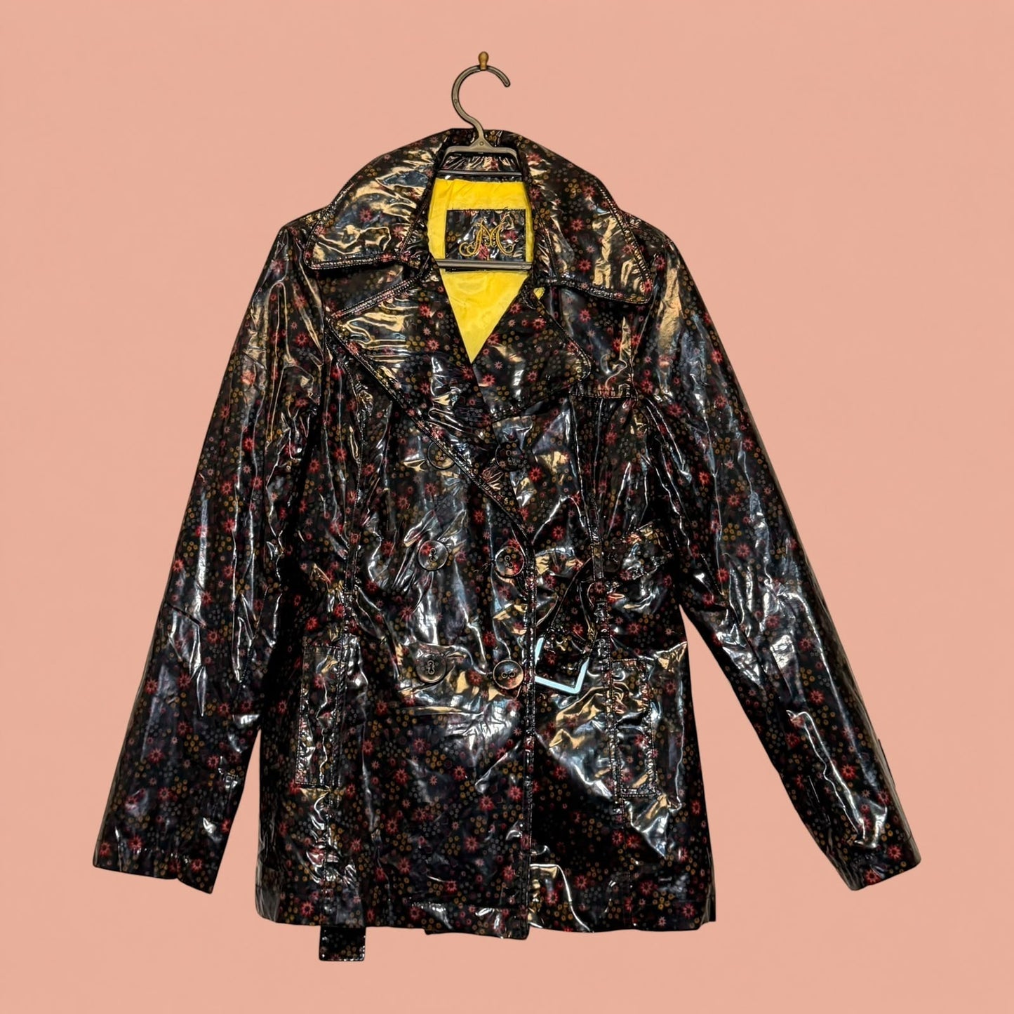 Chaqueta de eco cuero Tuclosetrenovado.cl negra con estampado floral, acabado brillante y forro interior amarillo.