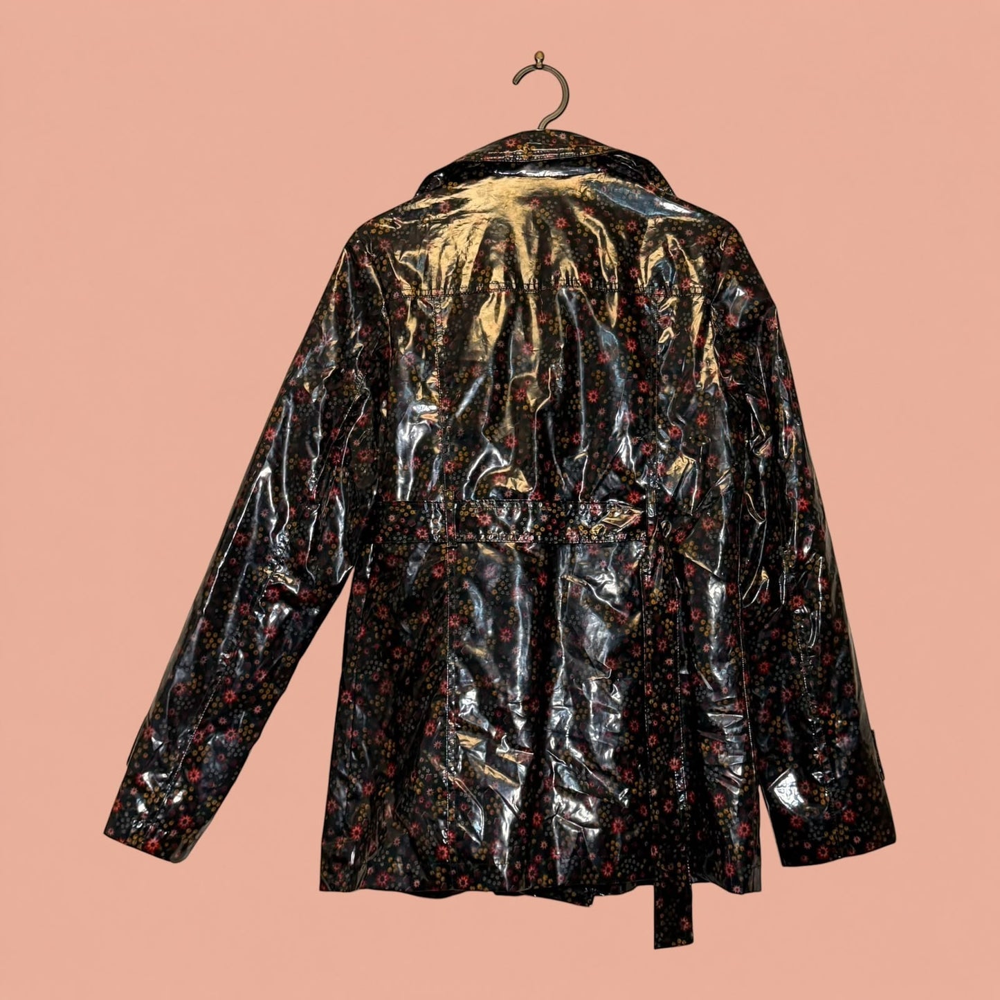 Chaqueta de Tuclosetrenovado.cl en eco cuero negro con estampado floral brillante y cinturón ajustable
