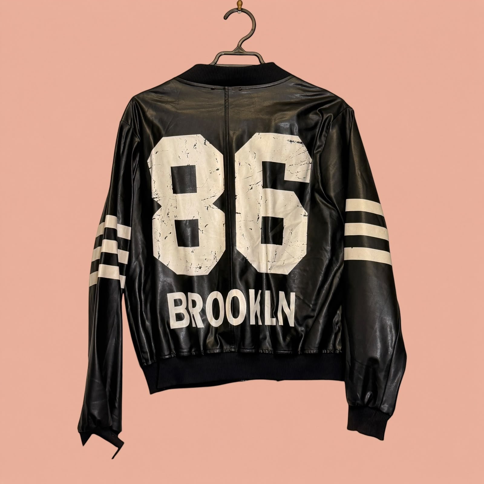 Chaqueta de eco cuero negra Tuclosetrenovado.cl con estampado 86 Brooklyn y rayas blancas en las mangas
