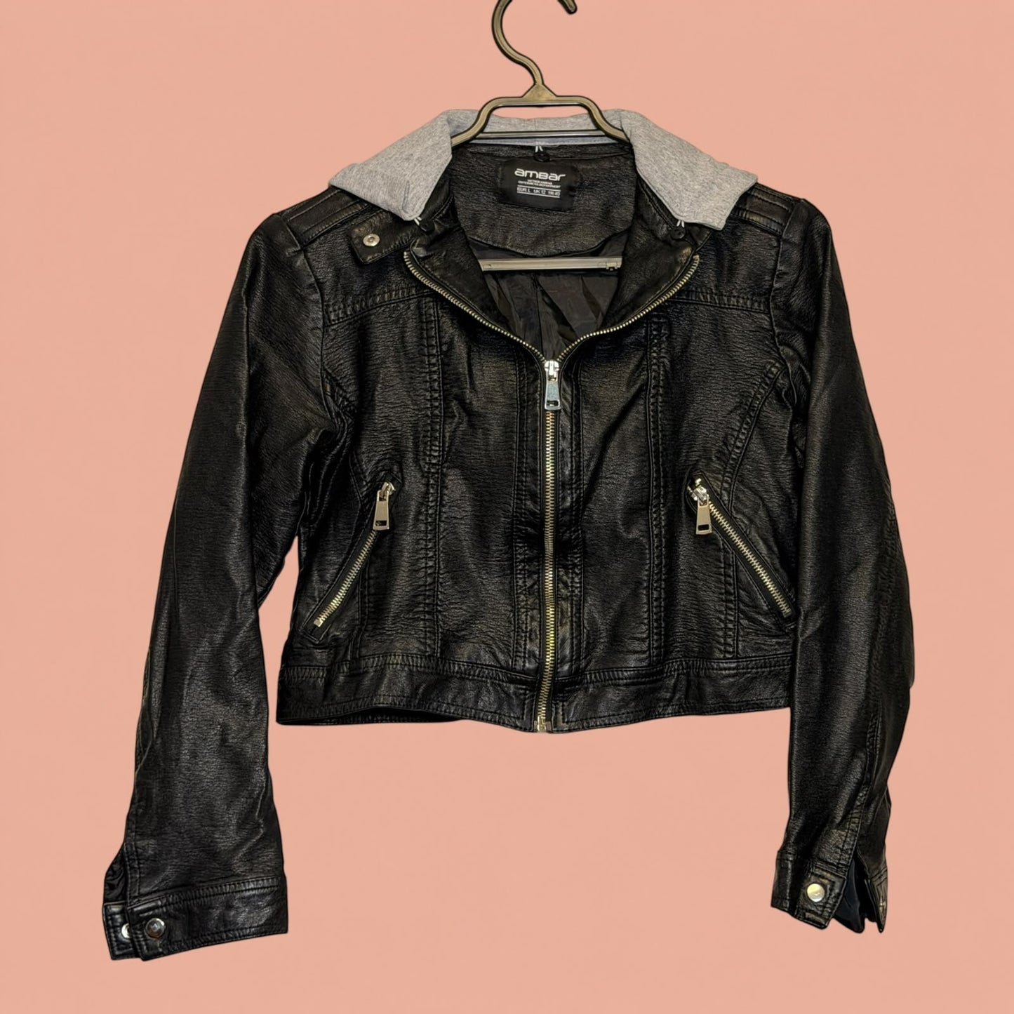 Chaqueta de eco cuero negra con capucha gris de Tuclosetrenovado.cl, estilo biker con cremalleras plateadas.