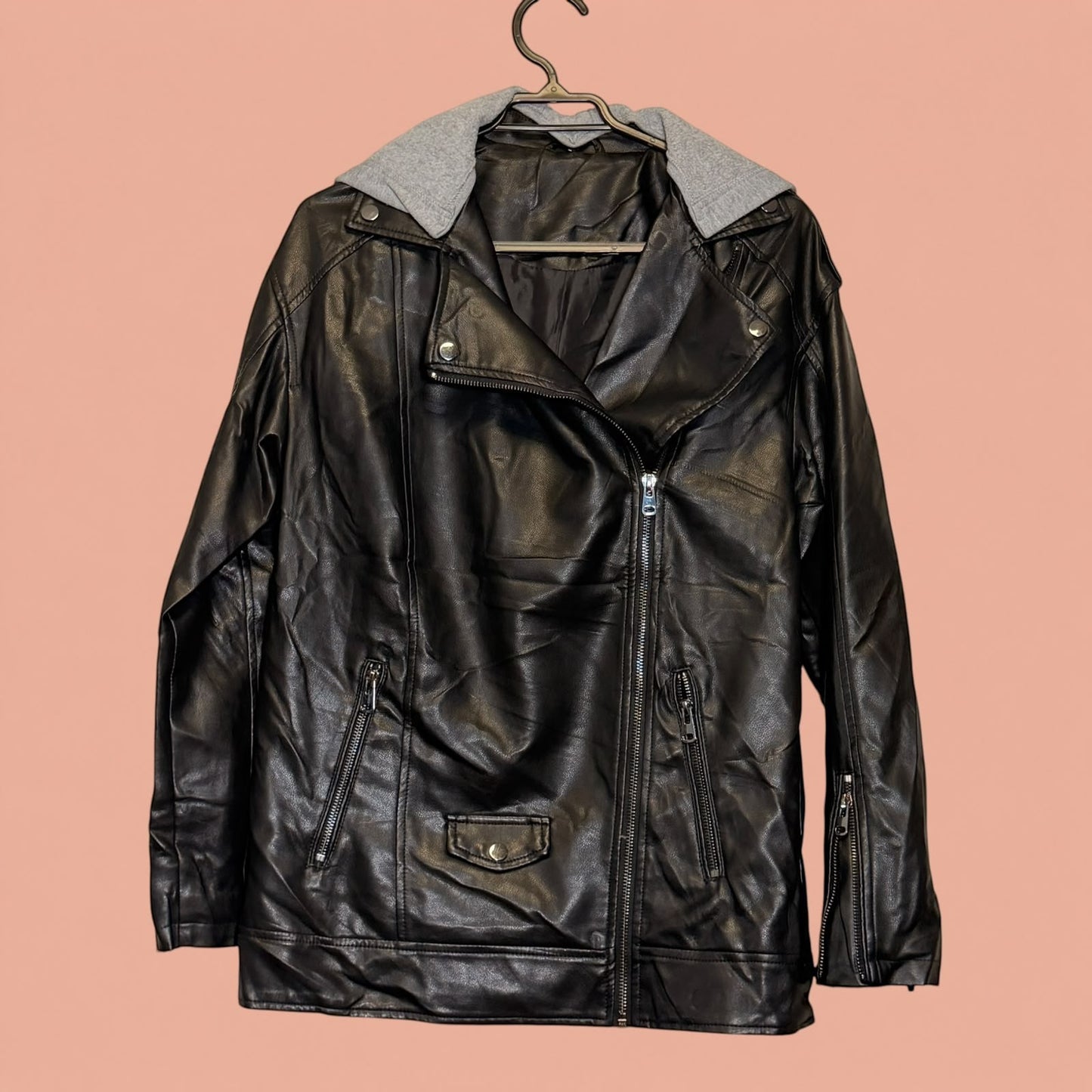 Chaqueta de eco cuero negra de Tuclosetrenovado.cl con capucha gris desmontable y cierre frontal asimétrico
