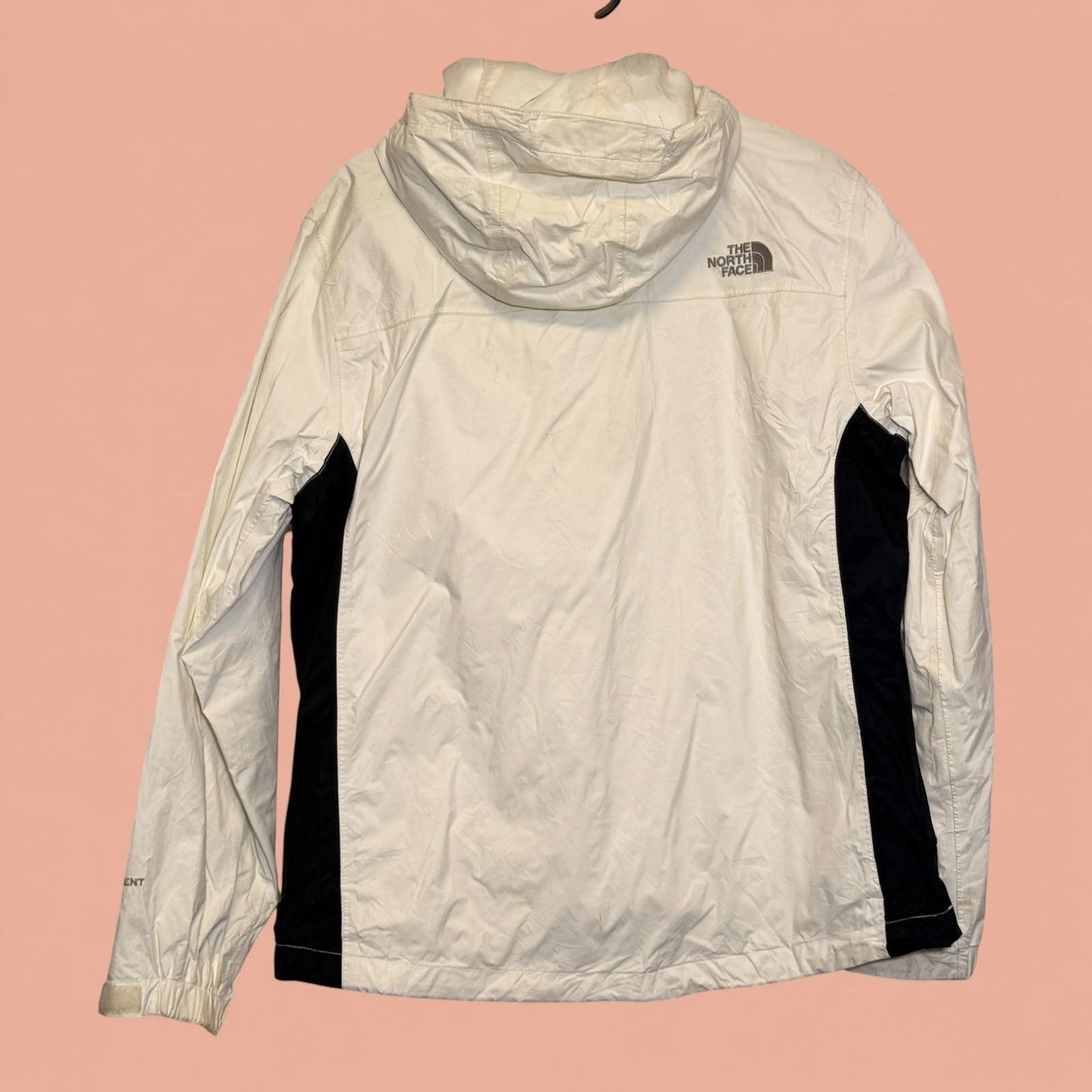 Chaqueta cortavientos blanca con capucha de The North Face en Tuclosetrenovado.cl, vista trasera con detalles negros