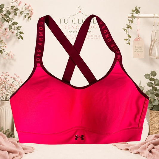 Sujetador deportivo Tuclosetrenovado.cl rosa intenso con tirantes cruzados y logo Under Armour en la parte inferior